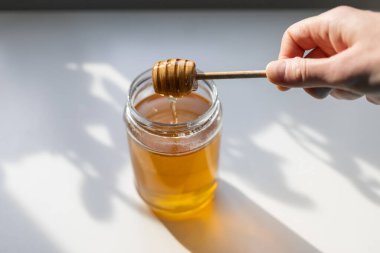 organik bal, ahşap bir kaptan cam bir kavanoza damlıyor.,