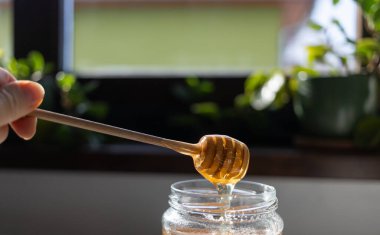 organik bal, ahşap bir kaptan cam bir kavanoza damlıyor.,