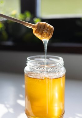 organik bal, ahşap bir kaptan cam bir kavanoza damlıyor.,