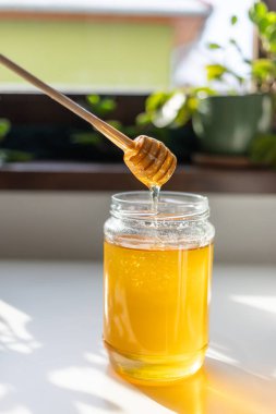 organik bal, ahşap bir kaptan cam bir kavanoza damlıyor.,