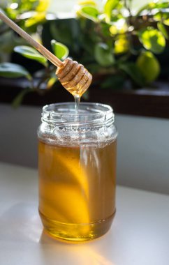 organik bal, ahşap bir kaptan cam bir kavanoza damlıyor.,