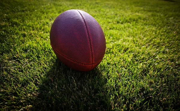 Close up of an american football on the field, players in the ba — Stock Photo, Image