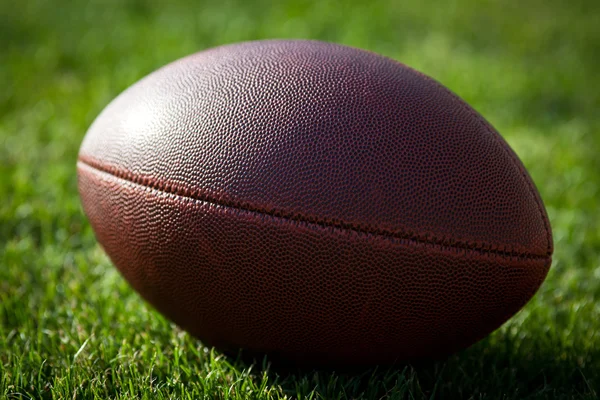 Close up of an american football on the field, players in the ba — Stock Photo, Image