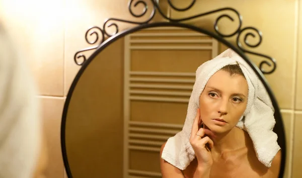 Middle-aged woman checking her face in bathroom mirror after sho — Stock Photo, Image