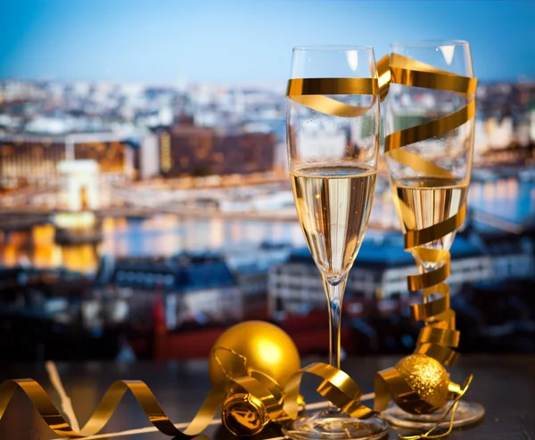 Új év, a város - pezsgős pohár és a város fényei a háttérben — Stock Fotó