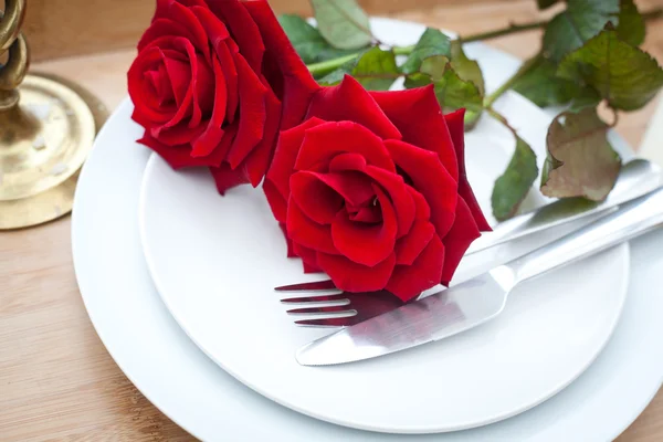 Tischdekoration mit roten Rosen auf Teller - zum Valentinstag — Stockfoto