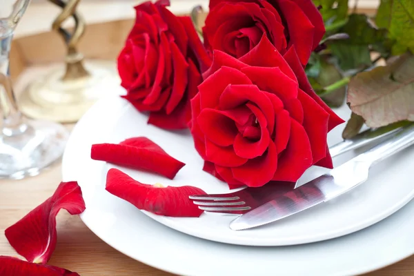 Tischdekoration mit roten Rosen auf Teller - zum Valentinstag — Stockfoto