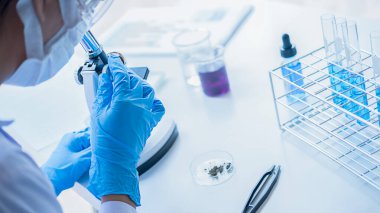 Tıbbi ya da bilimsel araştırmacı ya da insan doktoru laboratuarda bir test tüpü dolusu temiz çözeltiye bakıyor.