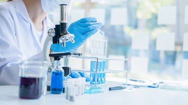 Tıbbi ya da bilimsel araştırmacı ya da insan doktoru laboratuarda bir test tüpü dolusu temiz çözeltiye bakıyor.