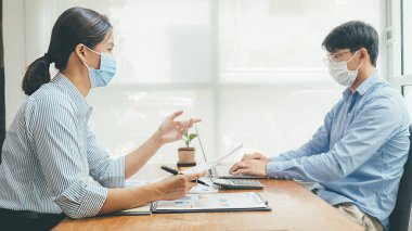 Asyalılar, tıbbi maske takarak ve çalışarak başarılı bir takım çalışması yaptılar. Coronavirus Salgını Durumu Arasındaki Özel Büro Sosyal Mesafesi Çalışması