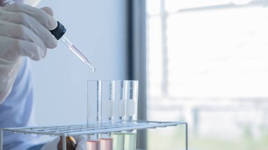 Tıbbi ya da bilimsel araştırmacı ya da insan doktoru laboratuarda bir test tüpü dolusu temiz çözeltiye bakıyor.