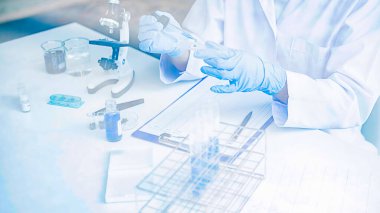 Tıbbi ya da bilimsel araştırmacı ya da insan doktoru laboratuarda bir test tüpü dolusu temiz çözeltiye bakıyor.