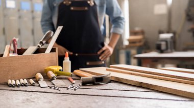 Marangoz, marangozhanedeki ahşap masada ekipmanla çalışıyor. Kadın bir marangozhanede çalışıyor..