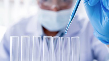 Tıbbi ya da bilimsel araştırmacı ya da insan doktoru laboratuarda bir test tüpü dolusu temiz çözeltiye bakıyor.