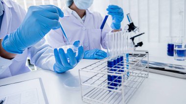 Tıbbi ya da bilimsel araştırmacı ya da insan doktoru laboratuarda bir test tüpü dolusu temiz çözeltiye bakıyor.