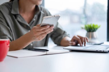 İş kadını iş yerinde ya da evde koltukta oturup dizüstü bilgisayar üzerinde çalışıyor ve şirket için iş planı ve stratejiler oluşturmak için çizelgeler ve grafikler üzerindeki verileri analiz ediyor ve kağıtlara yazıyor. İş konsepti.