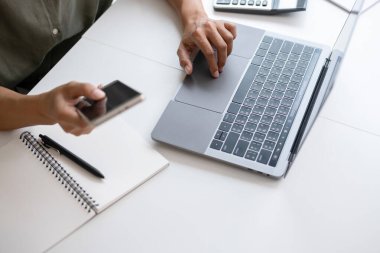 İş kadını iş yerinde ya da evde koltukta oturup dizüstü bilgisayar üzerinde çalışıyor ve şirket için iş planı ve stratejiler oluşturmak için çizelgeler ve grafikler üzerindeki verileri analiz ediyor ve kağıtlara yazıyor. İş konsepti.