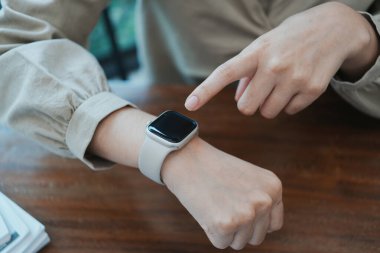 Masasında dizüstü bilgisayar ve kağıtlarla oturan genç ve güzel iş kadını ofiste ya da iş yerinde mutlu, sevinçli ve başarılı, tamamlanmış işi kutluyor. İş, başarı kavramı.