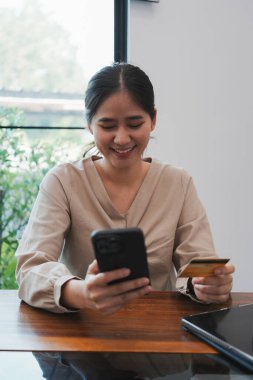 Masasında dizüstü bilgisayar ve kağıtlarla oturan genç ve güzel iş kadını ofiste ya da iş yerinde mutlu, sevinçli ve başarılı, tamamlanmış işi kutluyor. İş, başarı kavramı.