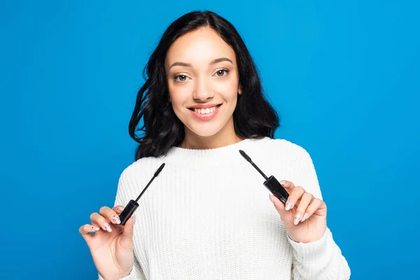 Sonriente Morena Mujer Sosteniendo Rímel Tubo Cepillo Aislado Azul — Foto de Stock