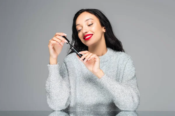 Gelukkig Brunette Vrouw Met Rode Lippen Kijken Naar Mascara Geïsoleerd — Stockfoto