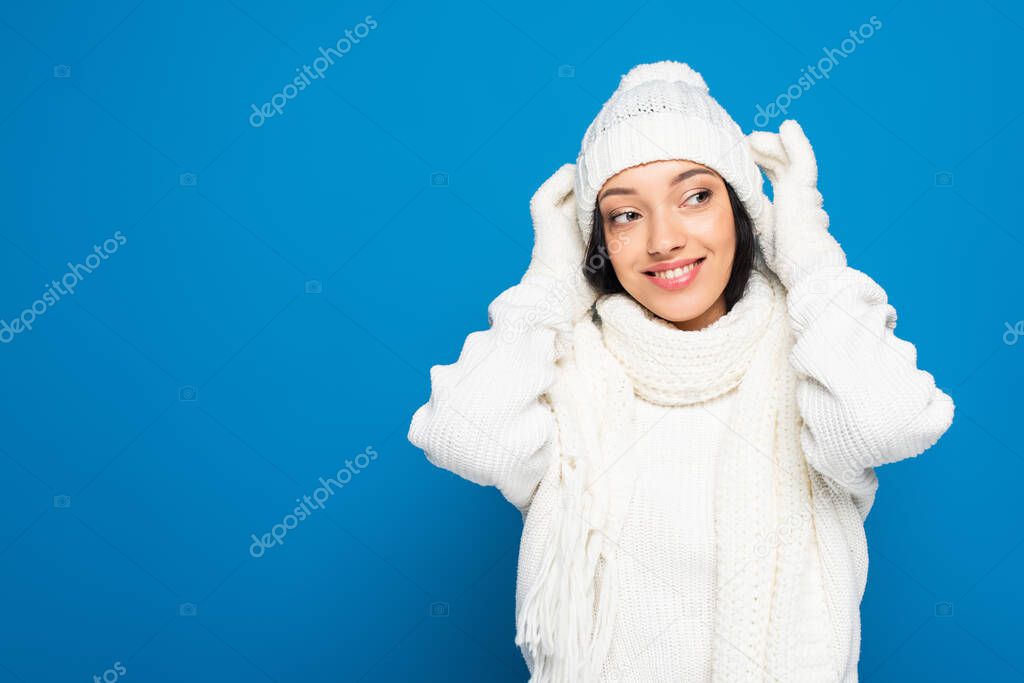 happy woman in winter outfit looking away isolated on blue