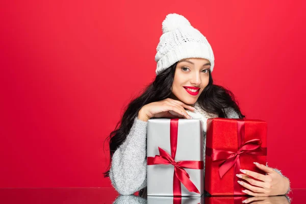 Glückliche Frau Mit Hut Umarmt Weihnachtsgeschenke Isoliert Auf Rot — Stockfoto