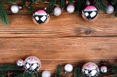 Kahverengi ahşap zemin üzerinde noel topları, çam dalları ve anason yıldızlarıyla yatıyordu.