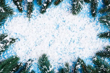 Flat lay with  pine branches and artificial snow on blue background clipart