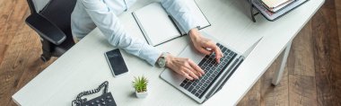 Cropped view of businesswoman typing on laptop, while sitting at workplace, banner clipart