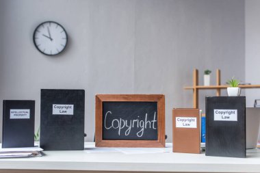 Entellektüel mülkiyet ve telif hakkı belgelerine sahip kitaplar bulanık arkaplanda doküman yığını bulunan masadadır