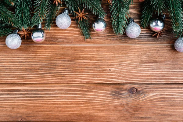 Top view of pine branches, baubles and anise stars on brown wooden background, new year concept