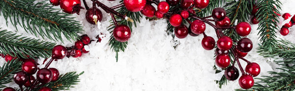 top view of spruce branches and artificial red berries on white textured background, banner