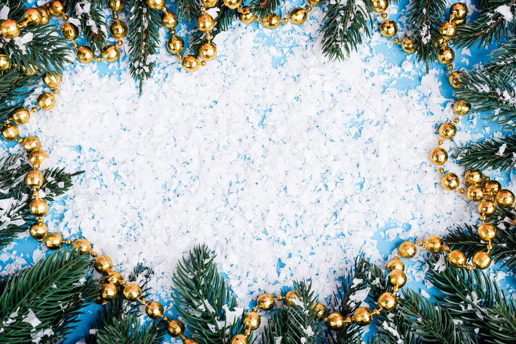 Flat lay with necklace, pine branches and artificial snow on blue background