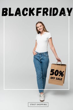Elinde alışveriş çantası olan neşeli genç bir kadın. Kara Cuma 'ya yakın bir yerde el ele dururken. Gri harflerde yüzde 50 indirim var.