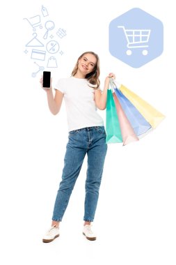 Renkli alışveriş çantalarının yanında boş ekranlı akıllı telefon tutan ve beyaz resimli bir kadın.