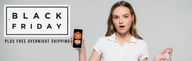 Kara Cuma harflerinin yanında akıllı telefonu tutan şok olmuş bir kadın ve gri afişte de illüstrasyon.