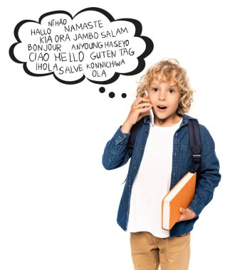 shocked and blonde schoolboy holding book and talking on smartphone near speech bubble with greeting words on white  clipart