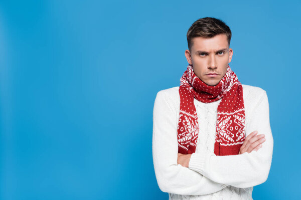 Недовольный мужчина со скрещенными руками смотрит на камеру, изолированную на голубом
