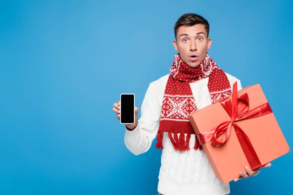 Surprised Man Gift Box Showing Smartphone Blank Screen Isolated Blue — Stock Photo, Image