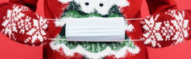 Kırmızıda izole edilmiş tıbbi maske takan eldivenli adam görüntüsü.