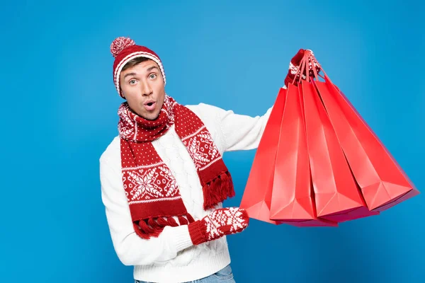 Homem Chocado Mitenes Levantando Sacos Papel Vermelho Enquanto Olha Para — Fotografia de Stock
