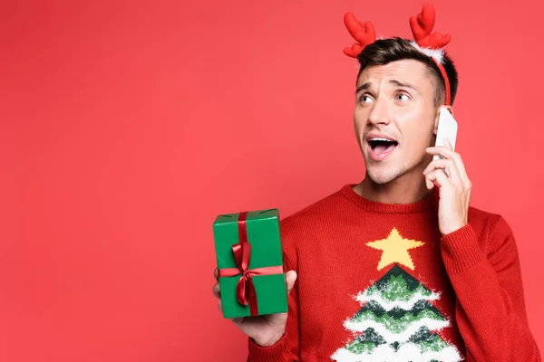 Excited Man Sweater Pine Tree Talking Smartphone Holding Gift Box — Stock Photo, Image
