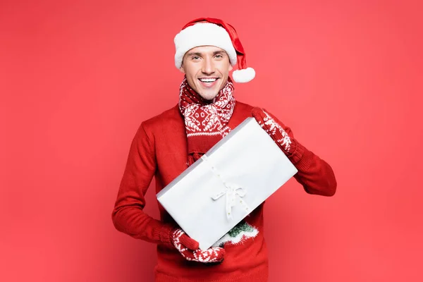Sorrindo Homem Mitenes Santa Chapéu Segurando Caixa Presente Fundo Vermelho — Fotografia de Stock