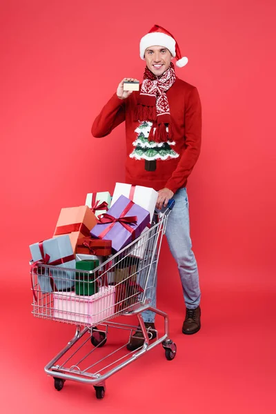 Sonriente Hombre Sombrero Santa Celebración Tarjeta Crédito Cerca Cesta Compra —  Fotos de Stock