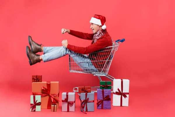 Side View Young Man Santa Hat Sitting Shopping Cart Gift — Stock Photo, Image