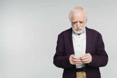 Gri renkte izole edilmiş akıllı telefon kullanan gömlekli ve ceketli yaşlı bir adam. 