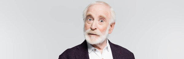 Surprised grey haired man looking at camera isolated on grey, banner