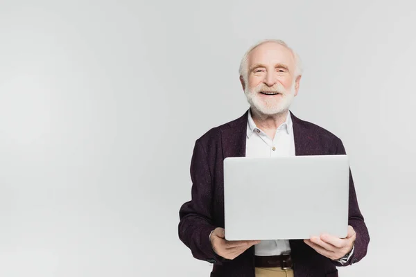 Улыбающийся Пожилой Человек Смотрит Камеру Держа Ноутбук Изолированным Сером — стоковое фото