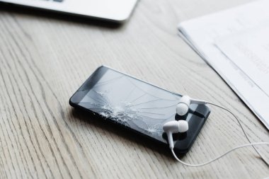 Parçalanmış ahşap arka planda akıllı telefonlu kulaklıkları kapat 